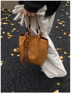 Detail der karamellbraunen Wildledertasche mit Schleifenstickerei und langen Fransen
