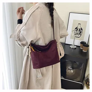 Détail du sac seau bordeaux en daim avec bandoulière tissée et pendentif ethnique
