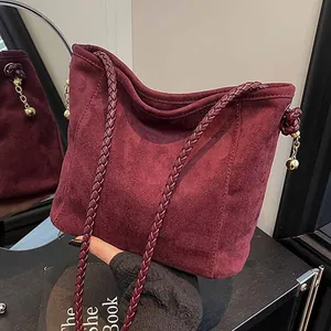 Grand sac seau bordeaux en daim avec bandoulière tressée et pendentif métallique