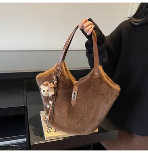 Gros plan sur un sac cabas en peluche marron avec anses en cuir et pendentif ours blanc