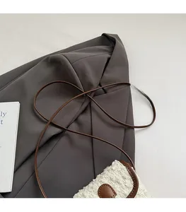 Detail of soft cream tweed texture and brown leather strap on minimalist crossbody bag