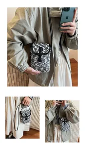 Detail of black and white bouclé crossbody phone bag with leather trim and buckle