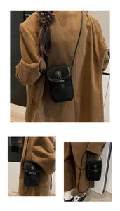 Detail view of retro black suede mini crossbody bag with a distinctive horn buckle closure