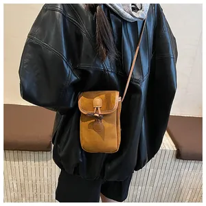 Detail of vintage camel suede crossbody bag featuring a classic toggle horn button closure