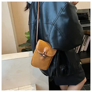 Detailed close-up of brown suede crossbody bag featuring a vintage toggle closure design