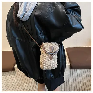 Detail of crossbody bag featuring textured beige fabric and vintage brown horn buckle