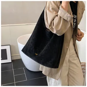 Détail du sac cabas noir mat minimaliste avec logo doré et texture effet daim luxueuse