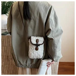 Detail of white plush crossbody bag with leather trim and toggle closure worn by model