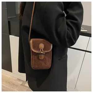 Close-up of a brown suede mini crossbody bag featuring a vintage horn buckle closure