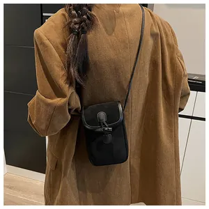 Detail of black canvas and faux suede crossbody bag with horn buckle on model