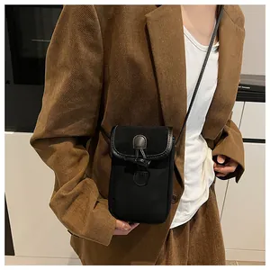 Detail of a black crossbody mini bag featuring a toggle closure on corduroy blazer