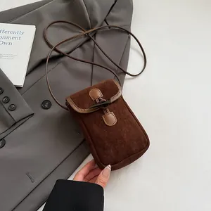 Detail of vintage horn buckle closure on a brown suede crossbody bag over a grey suit