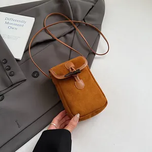 Close-up of brown suede mini crossbody bag with a vintage toggle button closure