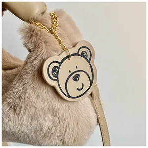 Détail de la texture en peluche kaki avec un charmant pendentif d'ours sur le sac