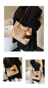 Detail of laser-cut flower hollow pattern on warm beige suede tote bag with brown strap