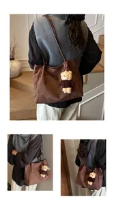 Detail of brown suede tote bag with floral cutouts and cute teddy bear charm
