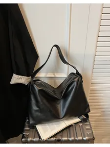 Detalle de un bolso hobo grande de piel sintética negra con cremallera plateada diaria