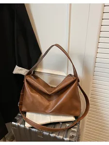 Detalle de un bolso Hobo grande de cuero sintético marrón sobre una maleta de viaje