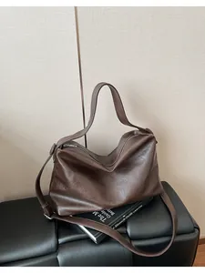Detalle de bolso tote de cuero suave marrón con cremallera plateada y correa ancha