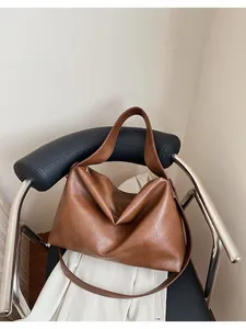 Detalle de un bolso hobo marrón vintage en una silla moderna para la oficina
