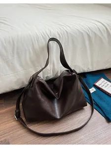 Detalle macro del bolso tote de piel sintética marrón oscuro con pliegues y herrajes plateados