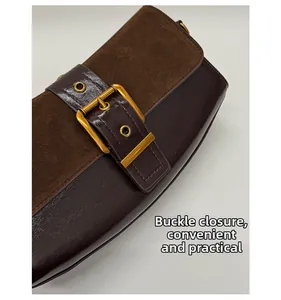 Detail of dark brown leather underarm bag with gold pin buckle and visible stitching