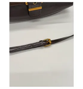 Detailed close-up of dark brown leather underarm bag featuring an adjustable gold buckle