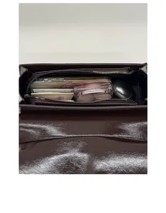 Internal view of dark brown gloss leather bag showing zipper pocket and daily essentials