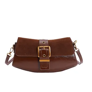 Detail of dark brown baguette bag with suede flap and large metal buckle strap