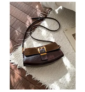 Close-up of retro brown underarm bag with gold buckle on a stylish white tassel rug