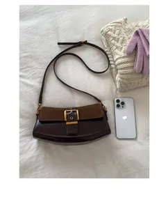 Detail of dark brown baguette bag featuring suede flap contrast and gold buckle