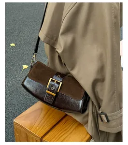 Detail of vintage patchwork leather shoulder bag with gold buckle on trench coat