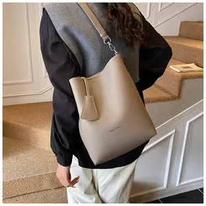 Détail du sac seau beige avec cuir au motif litchi et finition élégante