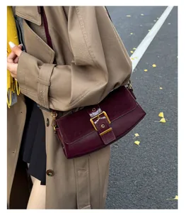 Detail of dark red shoulder bag with glossy leather and suede patchwork in outdoor setting