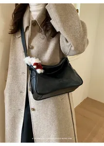 Sac sous le bras en cuir noir minimaliste avec breloque d'ours sur modèle en manteau