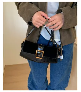Detail of black vintage underarm bag featuring a large gold buckle and leather textures