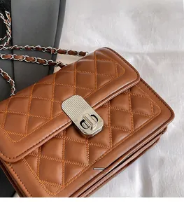 Detailansicht der braunen Stepptasche mit silbernem Druckschloss und Kettengurt