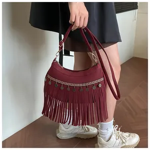 Détail de la broderie ethnique, pendentifs métalliques et franges sur sac bordeaux