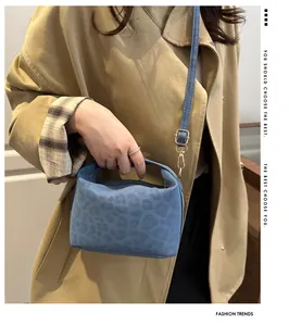 Detailed view of blue tote bag with leopard embossed texture and gold hardware on trench coat