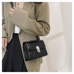 Nahaufnahme einer schwarzen Stepptasche mit Silberkette auf einem khakifarbenen Blazer