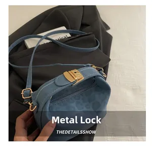 Detailed close-up of a blue crossbody bag showing gold push-lock and fine stitching