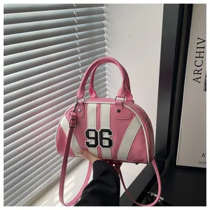 Dettaglio borsa bowling in pelle PU rosa e bianca con toppa numero 96 e borchie a stella