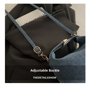 Detail of adjustable golden metal buckle on blue suede shoulder strap for tote bag