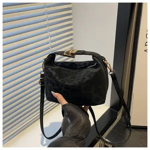 Detail of black leopard print tote with knot handle and golden metal lock hardware