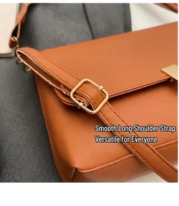 Détail de la bandoulière réglable avec boucle en métal doré sur le sac en cuir marron