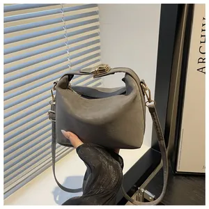 Close-up of gray frosted leather bag featuring a polished gold metal clasp lock