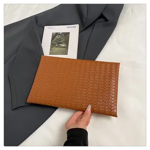 Vue détaillée de la texture tressée en cuir marron sur cette pochette enveloppe épurée