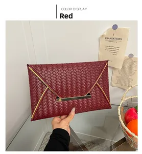 Détail d'une pochette enveloppe bordeaux avec motif tressé et garniture dorée