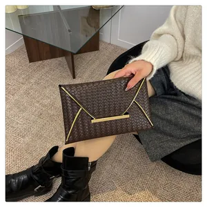 Détail de la pochette enveloppe tressée marron foncé avec fermoir en métal doré chic