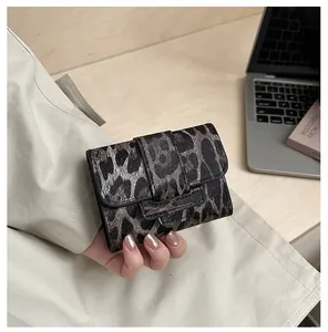 Gros plan d'un mini portefeuille plié à motif léopard tenu à la main pour un look stylé